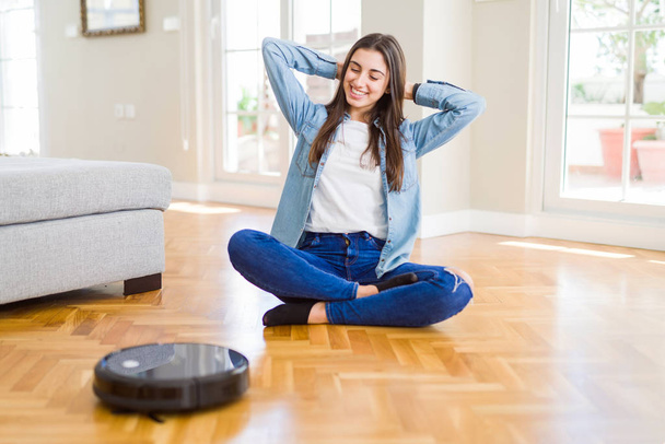Young woman using automatic vacuum cleaner to clean the floor, c - Photo, Image