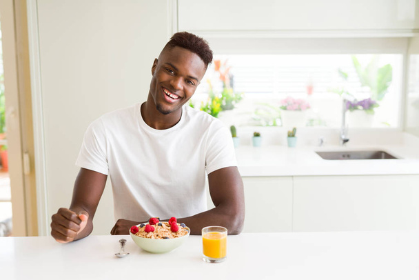 Hombre afroamericano guapo comiendo cereales y bayas como desayuno
 - Foto, imagen