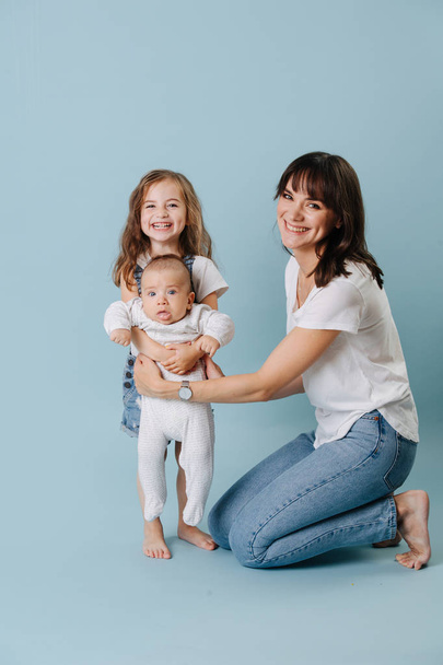 Family portrait of a mother with two daughters over blue background - Photo, Image
