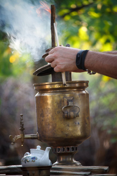 Accendere un vecchio samovar di bronzo, la posa di legna da ardere per riscaldare l'acqua per la preparazione del tè, messa a fuoco selettiva
 - Foto, immagini