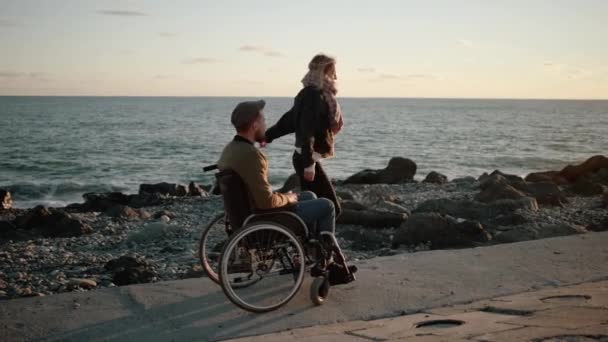 Ανάπηρος άνθρωπος και η υγιής φίλη του διασκεδάζουν στη θάλασσα ακτή, χορός - Πλάνα, βίντεο