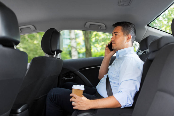 businessman with coffee calling on phone in car - Fotoğraf, Görsel