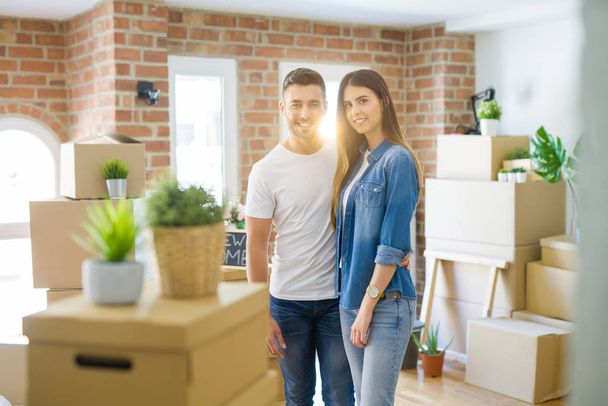 Schönes junges Paar zieht in ein neues Haus und lächelt glücklich in Kartons - Foto, Bild