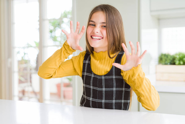 Young beautiful blonde kid girl wearing casual yellow sweater at home smiling funny doing claw gesture as cat, aggressive and sexy expression - Foto, Imagen