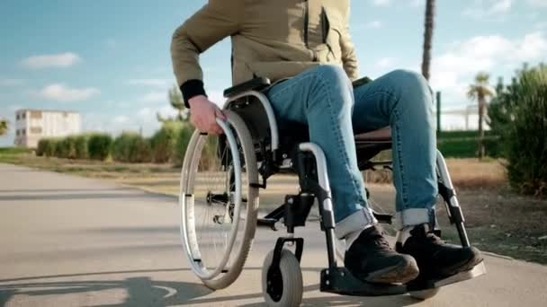 Giovane utente di sedia a rotelle maschile sta rotolando sulle strade della città, dettaglio vista delle gambe
 - Filmati, video