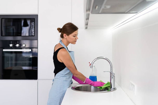 Giovane donna adulta lavello di pulizia in cucina
 - Foto, immagini