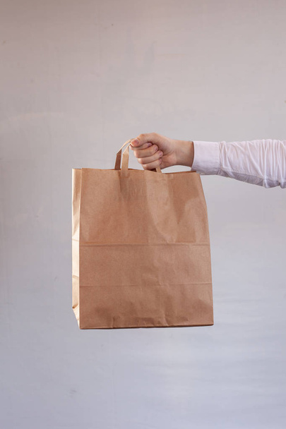 Genç kadın kahverengi bir teslimat zanaat kağıt torba taşıyor - Fotoğraf, Görsel
