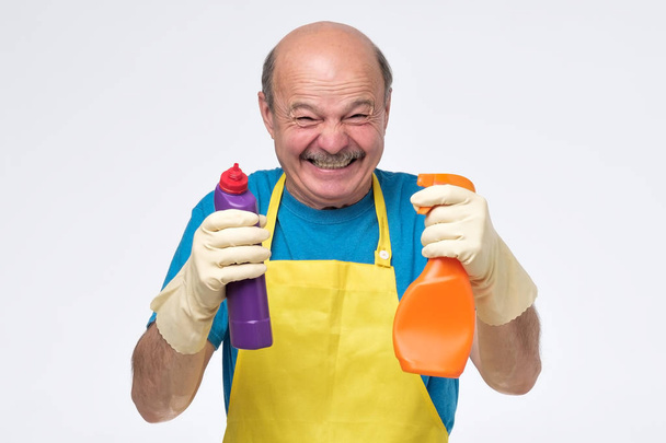 Muž s vtipnou grimasa z čistírny připravený na úklid bytu - Fotografie, Obrázek