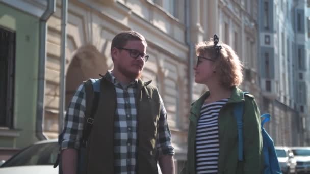 A loving couple walks around the city. A young family travels the world. Walks in the old city. Moscow courtyards. History Center. Young Man and Woman in glasses. Unusual tourists exploring the old city. They go hand in hand. - Felvétel, videó