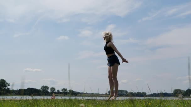 Mladá dívka skáče po trampolce a dělá ve vzduchu vlákna, pomalý pohyb - Záběry, video