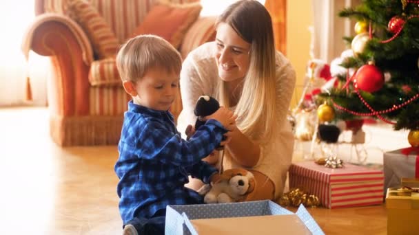 4k video o roztomilým chlapečku s matkou balit hračky do dárkových krabic, aby daroval dárky na Vánoce. Rodinné dárky poskytující a přijímané v zimních svátcích a slavností. - Záběry, video