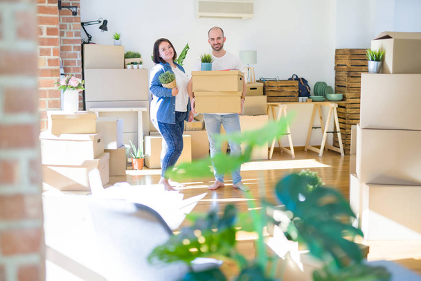 Νεαρό ζευγάρι που μετακομίζει σε ένα νέο σπίτι, χαμογελαστός χαρούμενος κρατώντας cardboa - Φωτογραφία, εικόνα