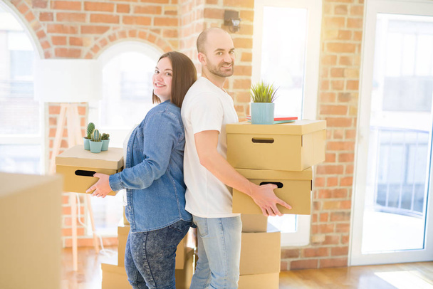 Young couple moving to a new home, smiling happy holding cardboa - Photo, Image