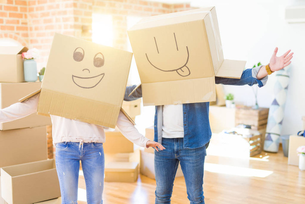 Couple having fun at new apartment wearing boxes with funny faces over head - Photo, Image