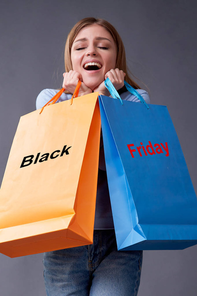 Černý pátek, koncept nakupování a obchodu. Saké a slevy. Žena se zavazadly na šedém pozadí. - Fotografie, Obrázek