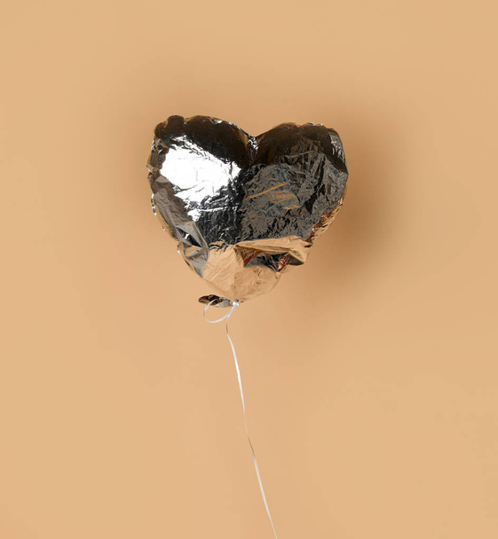 Party is over deflated silver heart balloon object  on beige background with shadow - Foto, afbeelding
