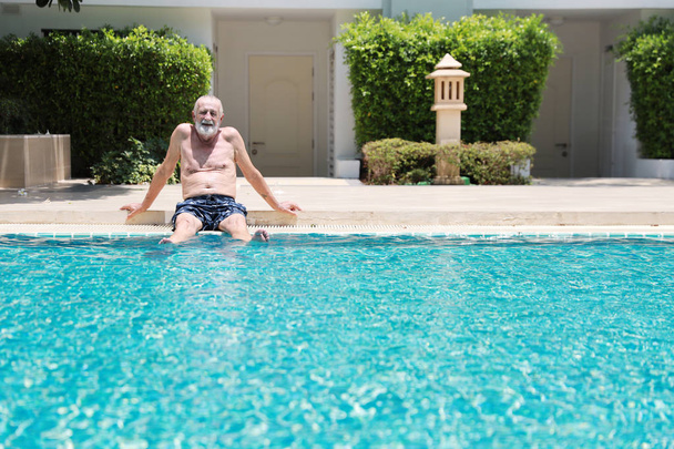 felice anziano caucasico prendersi una pausa mentre nuota in piscina durante la vacanza di pensionamento con relax e sorridente
 - Foto, immagini