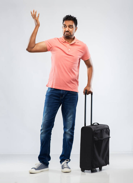 indian man in polo shirt with travel bag shrugging - Foto, Bild