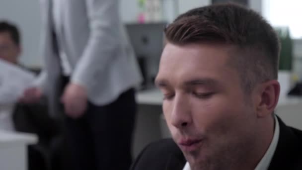 Man eat at the office, lunch, people work behind him. - Materiał filmowy, wideo