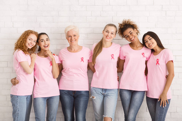Monietninen naisten rintasyöpä T-paidat halaus yli valkoinen seinä
 - Valokuva, kuva