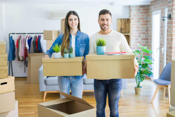 Jeune couple déménageant dans une nouvelle maison, souriant heureux tenant boîtes en carton dans un nouvel appartement
 - Photo, image