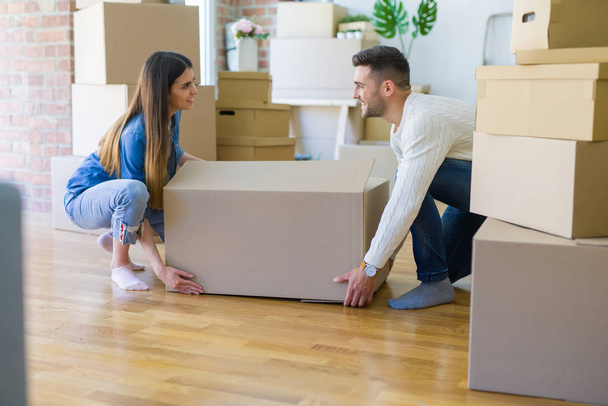 Beau jeune couple déménageant dans une nouvelle maison, tenant une grande boîte en carton
 - Photo, image
