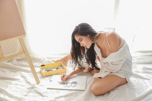 азіатська жінка-художник у білій сорочці малює картину з олівцем у вітальні (концепція жіночого способу життя
) - Фото, зображення