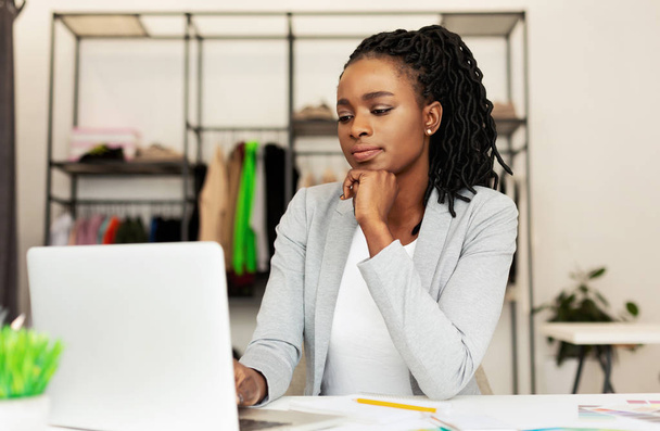 Fiatal afro üzletasszony használ laptop-ban öltözet készlet - Fotó, kép