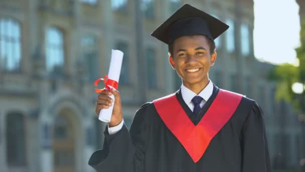 Radostný vysokoškolský student předvádějící diplom slavící maturitní den, úspěch - Záběry, video