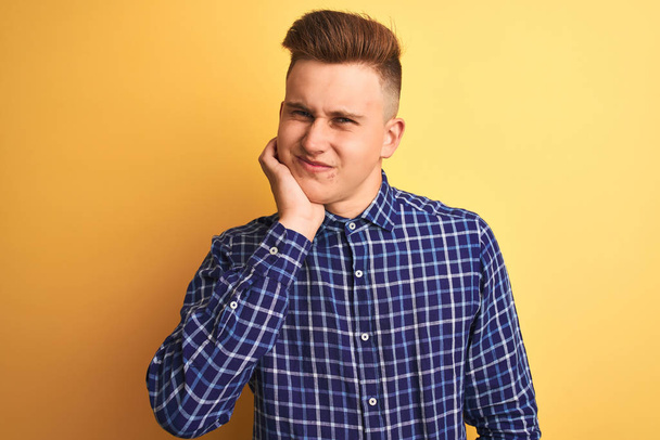 Молодой красивый мужчина в повседневной рубашке стоит на изолированном желтом фоне, касаясь рта с болезненным выражением лица из-за зубной боли или зубной болезни на зубах. Концепция дантиста
. - Фото, изображение