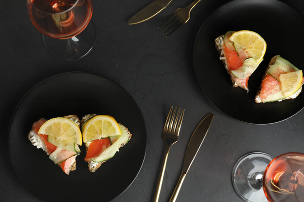 Flat lay composition with delicious bruschettas with salmon on black table - Fotó, kép