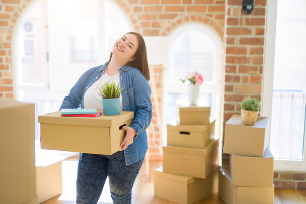 Young beautiful plus size woman moving to a new house, holding c - Photo, Image