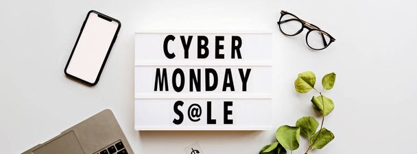 Creative promotion composition Cyber monday sale text on lightbox, laptop, mobile phone on white background. Horizontal banner for web design. Flat lay, top view, overhead, mockup, template - 写真・画像