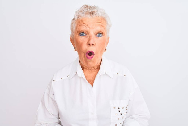 Senior mulher de cabelos grisalhos vestindo camisa elegante em pé sobre fundo branco isolado com medo e chocado com expressão surpresa, medo e rosto animado
. - Foto, Imagem