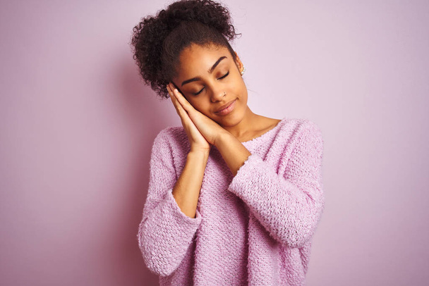 Young african american woman wearing winter sweater standing over isolated pink background sleeping tired dreaming and posing with hands together while smiling with closed eyes. - Zdjęcie, obraz