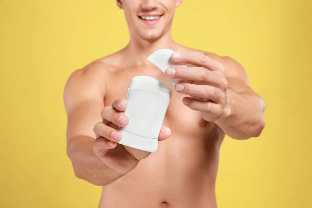 Young man with deodorant on yellow background, closeup - Zdjęcie, obraz