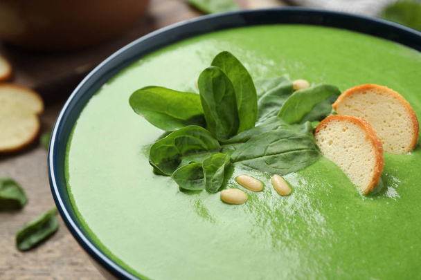 Bowl of healthy green soup with fresh spinach on wooden table, closeup view - Foto, Imagem