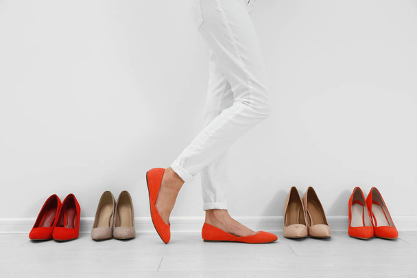 Woman trying on different shoes near white wall, closeup - Foto, immagini