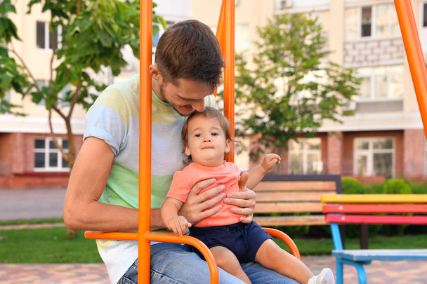 Father with adorable little baby on swing outdoors. Happy family - Fotó, kép