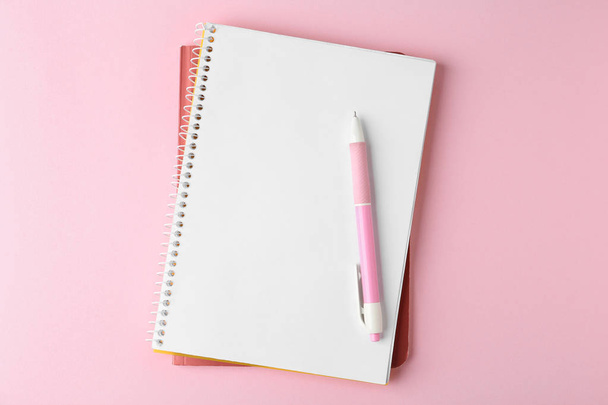 Cadernos e caneta sobre fundo rosa, vista superior
 - Foto, Imagem