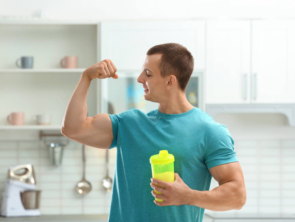 Sportowy młody człowiek z białkiem wstrząsnąć w kuchni - Zdjęcie, obraz