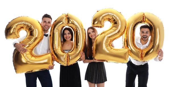 Happy young friends with golden 2020 balloons on white background. New Year celebration - Foto, Imagen