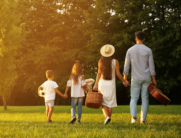 Happy family with picnic basket in park - Foto, Imagen