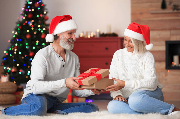 Happy couple opening Christmas gift at home - 写真・画像