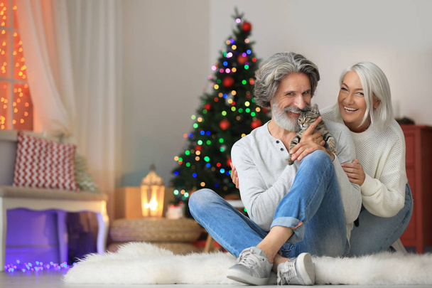 Happy couple with cute cat celebrating Christmas at home - Foto, Imagem