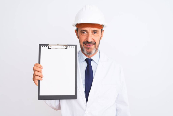 Senior engineer man wearing security helmet holding clipboard over isolated white background with a confident expression on smart face thinking serious - Photo, image