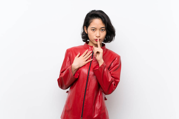 asiatische junge Frau über isoliertem weißem Hintergrund zeigt ein Zeichen des Schweigens Geste legt den Finger in den Mund - Foto, Bild