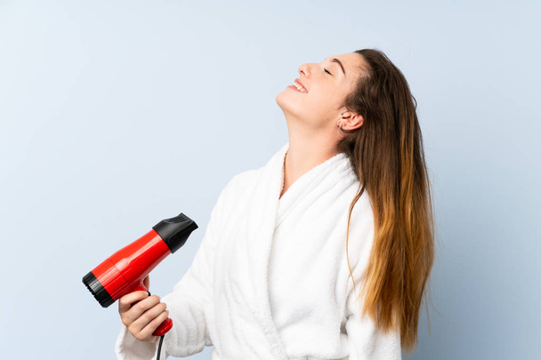 Nuori nainen kylpytakissa hiustenkuivaajalla
 - Valokuva, kuva