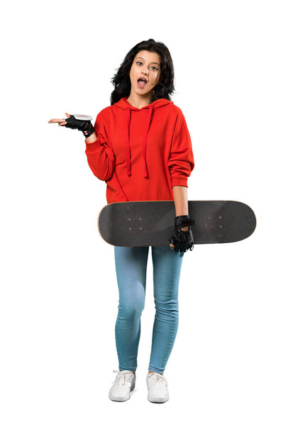A full-length shot of a Young skater woman with shocked facial expression over isolated white background - Φωτογραφία, εικόνα
