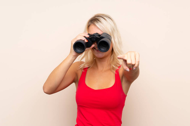 Mujer rubia joven sobre fondo aislado con prismáticos negros
 - Foto, imagen